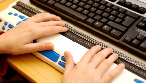 Hände auf einer Braille-Tastatur